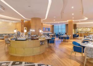 un restaurante con mesas y sillas y un bar en Embassy Suites By Hilton Doha Old Town, en Doha