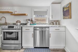 uma cozinha com armários brancos e um aparelho de aço inoxidável em Lake Cottage Getaway em Portland