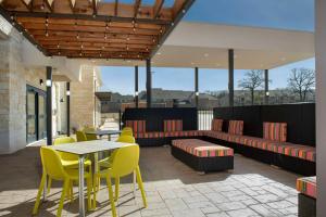 a patio with yellow chairs and a table and chairs at Home2 Suites By Hilton Flower Mound Dallas in Flower Mound