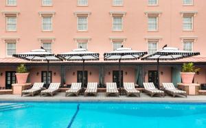 a hotel pool with lounge chairs and umbrellas at Mills House Charleston, Curio Collection by Hilton in Charleston