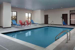 Flower MoundにあるHome2 Suites By Hilton Flower Mound Dallasの青と赤の椅子が備わるホテルルームのプールを利用できます。