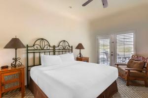 um quarto com uma grande cama branca e uma cadeira em Hilton Vacation Club Rancho Manana em Cave Creek