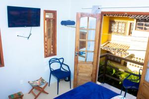 a room with a balcony with two chairs and a tv at Suíte na vila de Praia do Forte in Praia do Forte