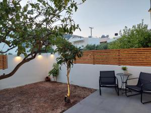 un patio con 2 sedie, un tavolo e un albero di MG elounda apt a Eloúnda