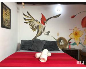 a bedroom with a bed with a bird on the wall at Beija Flor Hostel in Villa de Leyva