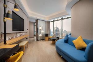 Hilton Garden Inn Shanghai Lujiazui في شانغهاي: غرفة معيشة مع أريكة زرقاء وتلفزيون