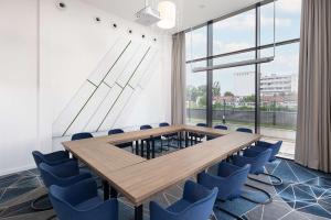 una sala de conferencias con una mesa de madera y sillas azules en Hampton By Hilton Targu Mures, en Târgu Mureș