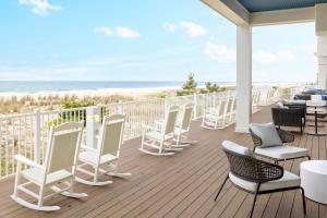 a deck with chairs and tables and a view of the beach at Hilton Garden Inn Ocean City Oceanfront in Ocean City