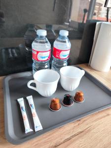 a tray with two bottles of water and two measuring cups at Luminoso Apartamento enfrente del AVE in Puertollano