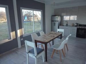a kitchen with a wooden table and white chairs at Cardo Ruso Cabaña in Toay
