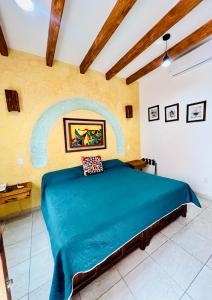 a bedroom with a blue bed with a painting on the wall at Los Arrayanes in Oaxaca City