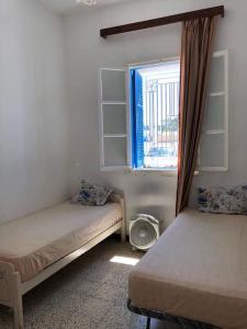 a small room with two beds and a window at Une maison djerbienne in Houmt Souk