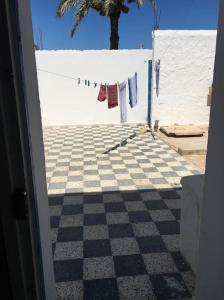 a room with a checkered floor and a clothes line with towels on at Une maison djerbienne in Houmt Souk