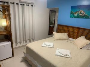 um quarto com uma cama com duas toalhas brancas em Pousada Flôr do Atlântico em Fernando de Noronha