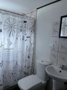 y baño con cortina de ducha, aseo y lavamanos. en Alturas de Bocatoma, en Río Blanco