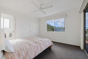 a white bedroom with a bed and a window at Sunrise at Smiths Beach in Smiths Beach