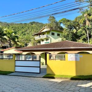 a yellow and white house with a garage at Hotel Bem Te Vi in Ubatuba