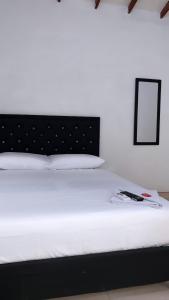 ein weißes Bett mit einem schwarzen Kopfteil in einem Zimmer in der Unterkunft HOTEL BOUTIQUE CRISTOFF in Apartadó