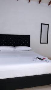 アパルタドにあるHOTEL BOUTIQUE CRISTOFFの部屋にある黒いヘッドボードが付いた白いベッド +2枚の写真