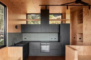 a kitchen with a black counter top and wooden walls at Bridge Rest - Wye River house with sauna in Wye River