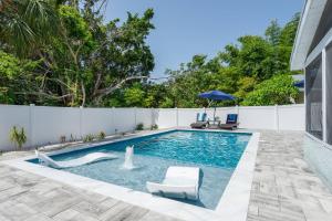 a swimming pool with two chairs and an umbrella in a backyard at Quaint Cottage in a South Sarasota Neighborhood in Sarasota