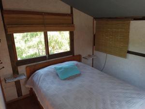 1 dormitorio con 1 cama y 2 ventanas en Natural Mistic, en Punta del Diablo