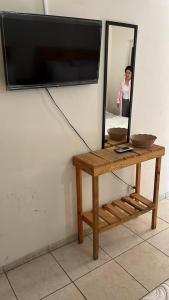 a mirror on a wall with a table and a tv at Hotel Regina “El Llano” in Cosalá