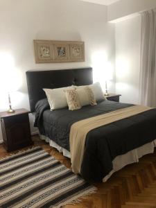 una camera da letto con un letto con lenzuola nere e cuscini bianchi di Cómodo y cálido a Buenos Aires