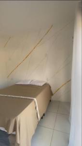 a bed in a room with a white wall at Maceió Kite House in Camocim
