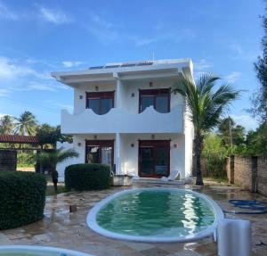a villa with a swimming pool in front of a house at Maceió Kite House in Camocim