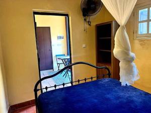 Petit Studio - île de Gorée في غوري: غرفة نوم مع سرير وملاءات زرقاء وغرفة مع مرآة