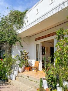 a white house with a porch with plants at Hat De homestay in Xuan An