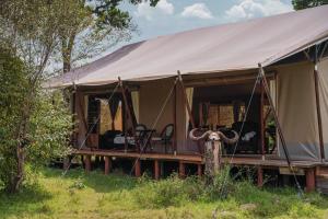 a tent with chairs in it in a field at Enkusero Mara in Aitong