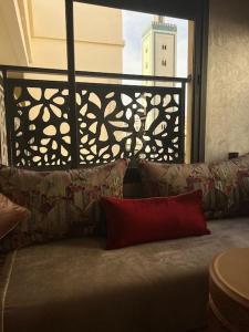 a couch with pillows in front of a window at Logement moderne et neuf entièrement équipé in Fez