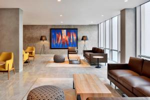 a living room with couches and a large painting on the wall at Aloft New Delhi Aerocity in New Delhi