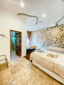 1 dormitorio con cama y pared de piedra en De Summit Villa & View, en Puncak