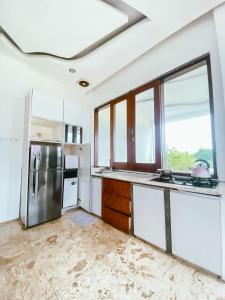 a kitchen with white cabinets and a large window at De Summit Villa & View in Puncak