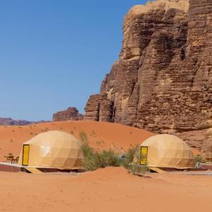two domes in the desert next to a cliff at Wadi Rum Camp in Wadi Rum