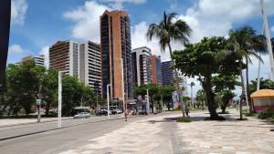 una calle de la ciudad con edificios altos y palmeras en Belíssimo frente mar 107, en Fortaleza