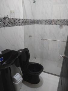 a bathroom with a black toilet and a shower at Casa Mompox in Mompos