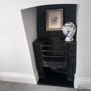 a black cabinet with a vase and a picture at Hideaway Cottage - Private ensuite room - 4 minutes to the sea! in Sandgate
