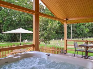 a jacuzzi tub on a deck with a table and chairs at Alpaca Lodge in Barkston