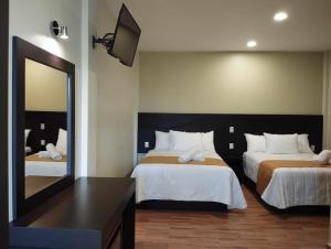 Habitación de hotel con 2 camas y espejo en Hotel & Cabañas Malinche en Huamantla