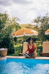 a woman sitting in a chair reading a book next to a swimming pool at Enkusero Mara in Aitong