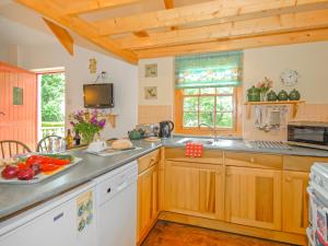 una cucina con armadi in legno e piano di lavoro di Inglenook Cottage a Landshipping