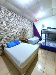 a bedroom with two beds and a brick wall at Hostal Leyendas in León