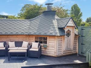 a wooden cabin with two chairs and a roof at The Hideaway in Chapel Saint Leonards