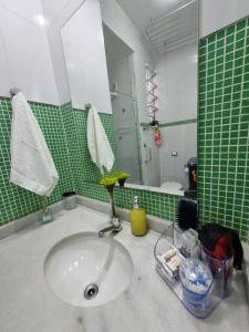 a bathroom with a sink and a green tiled wall at Apartamento no Centro de Cabo Frio in Cabo Frio