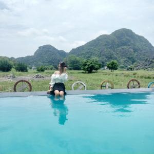een vrouw aan de rand van een zwembad bij Hang Mua Bungalow in Ninh Binh