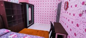 Pokój z różową ścianą ze stołem i krzesłami w obiekcie Homestay Kluang 309 
